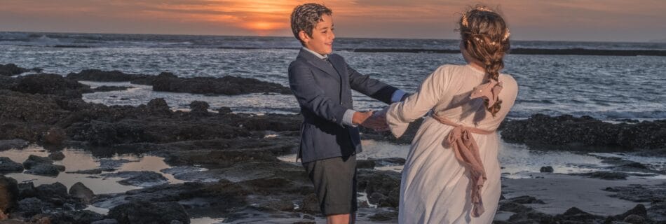 Niños vestidos de comunión jugando en la playa al atardecer en el Puerto de Santa María