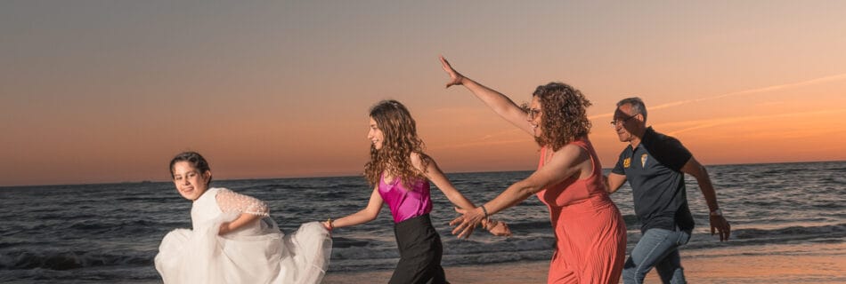 Niña sonriente con vestido de comunión apoyada en una baranda de madera en un entorno natural durante el atardecer.
