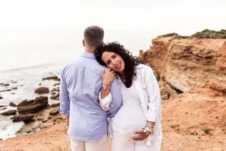 Fotografía de maternidad de pareja caminando en la orilla de la playa