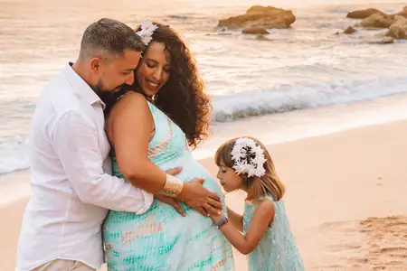 Sesión de maternidad con niño pequeño abrazando a su mamá embarazada