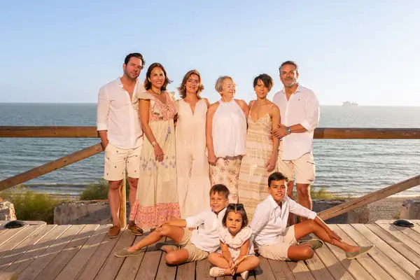 Familia posando de forma relajada junto al mar, fotografía emocional con estilo natural.