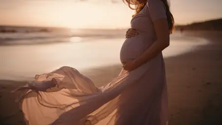 Sesión de maternidad en la playa, futura mamá sentada mirando al horizonte
