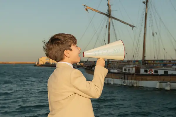 Niño de comunión jugando en la playa de Cádiz con su vela