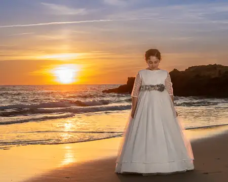 Niña de comunión en la playa con puesta de sol